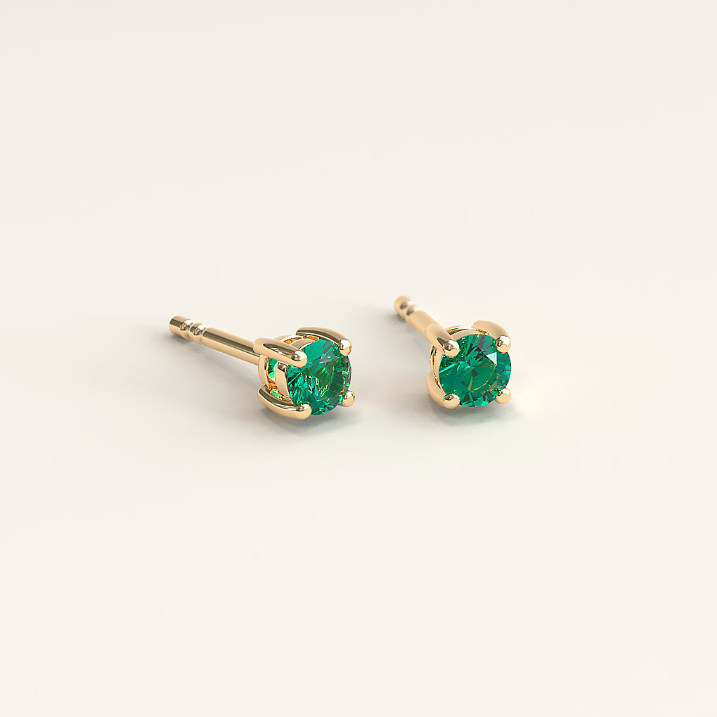 A pair of 18k gold stud earrings with 2.5mm round Colombian emeralds.