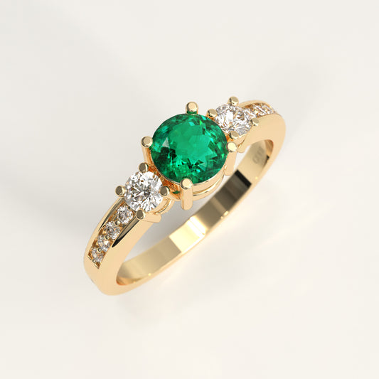 A yellow gold ring featuring a round-cut green emerald center stone and small diamonds accent stones on the shoulders, shown on a clean white background.