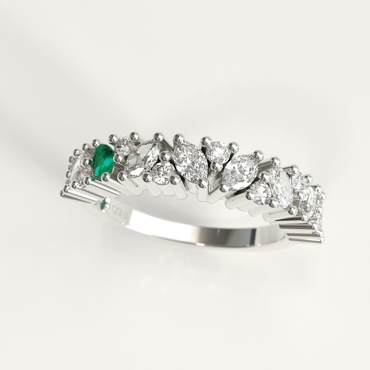 A 18k white gold diamond band ring featuring a row of marquise-cut and round diamonds with a single prominent green marquise emerald on the left, set against a clean white background.