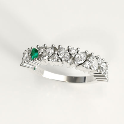 A 18k white gold diamond band ring featuring a row of marquise-cut and round diamonds with a single prominent green marquise emerald on the left, set against a clean white background.