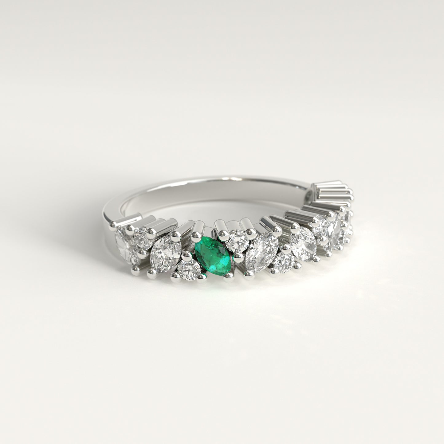 lateral view of a 18k white gold diamond band ring featuring a row of marquise-cut and round diamonds with a single prominent green marquise emerald on the left, set against a clean white background.