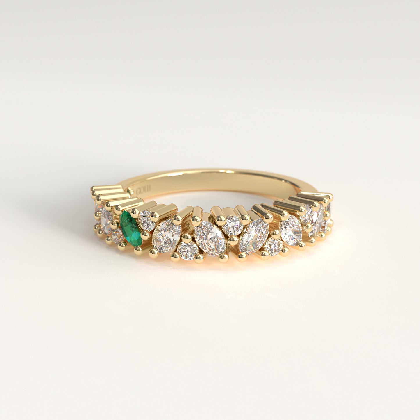 A yellow 18 k gold eternity-style ring featuring a row of round and marquise-cut diamonds with one prominent colombian emerald marquise-cut, shown on a light gray background.