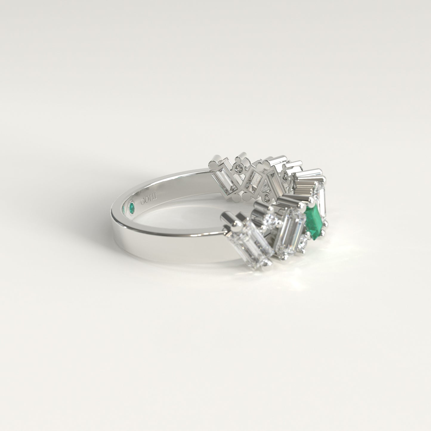 A white gold ring featuring a cluster of baguette-cut natural diamonds and a Colombian emerald baguette-cut gemstone, photographed on a clean white background. Lateral view