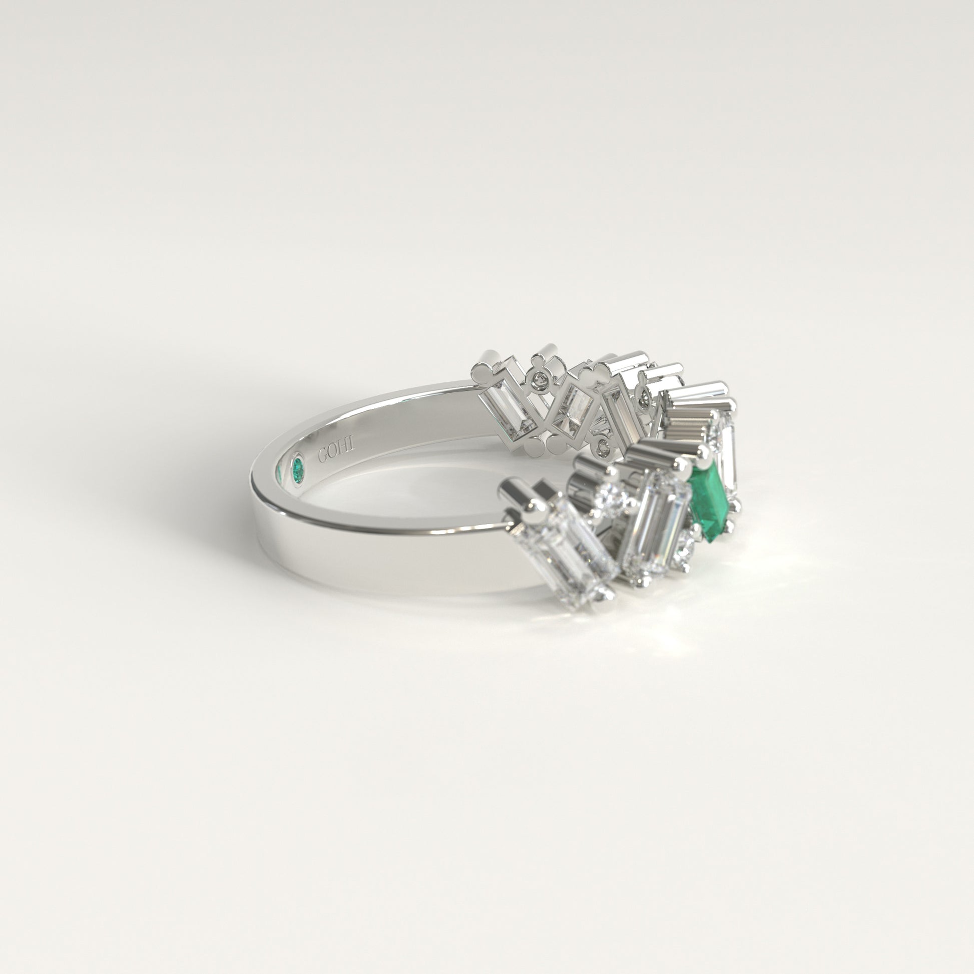 A white gold ring featuring a cluster of baguette-cut natural diamonds and a Colombian emerald baguette-cut gemstone, photographed on a clean white background. Lateral view
