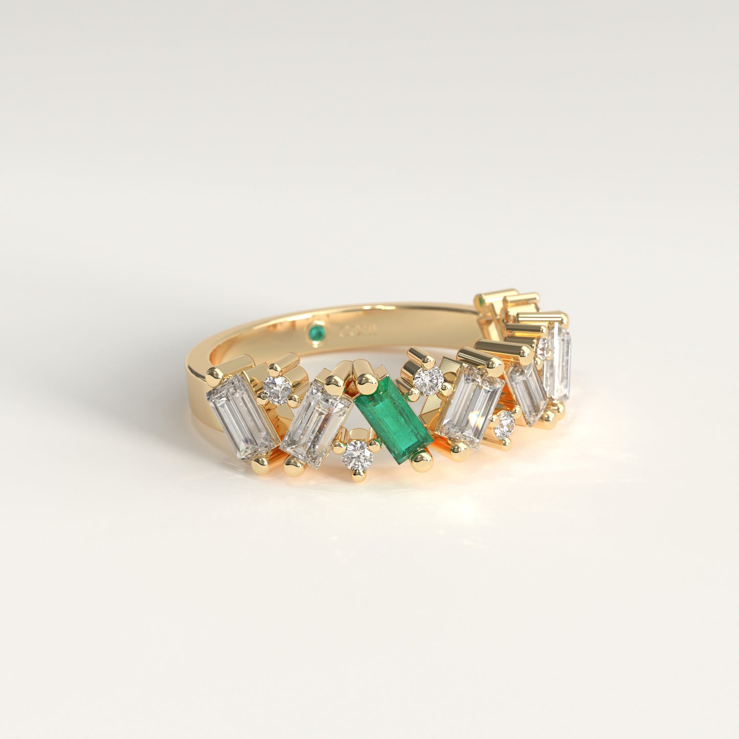 A 18k fairmined gold band ring featuring a row of diamonds baguette and round-cut  with a prominent green Colombian emerald emerald-cut center stone, photographed on a clean white background.