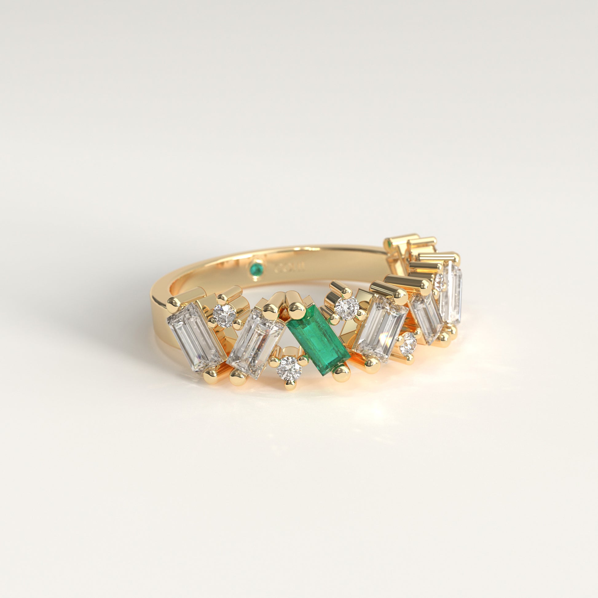 A 18k fairmined gold band ring featuring a row of diamonds baguette and round-cut  with a prominent green Colombian emerald emerald-cut center stone, photographed on a clean white background.