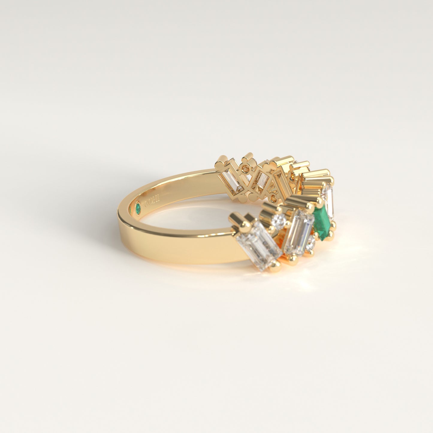 A gold ring featuring a cluster of baguette-cut diamonds and a single green emerald-cut stone, photographed on a clean white background. Lateral View