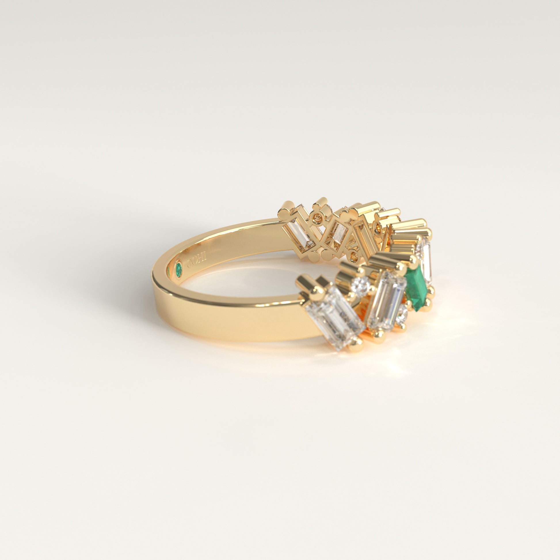A gold ring featuring a cluster of baguette-cut diamonds and a single green emerald-cut stone, photographed on a clean white background. Lateral View
