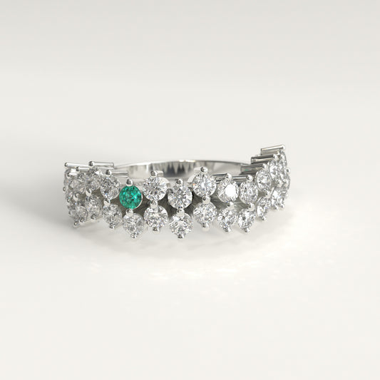 Stratum Ring in 18k fairmined white gold with a tiered row of round brilliant diamonds set in a zigzag pattern, and one round Colombian emerald bezel-set among them at the center. Smooth polished white gold band beneath the sparkling stone cluster