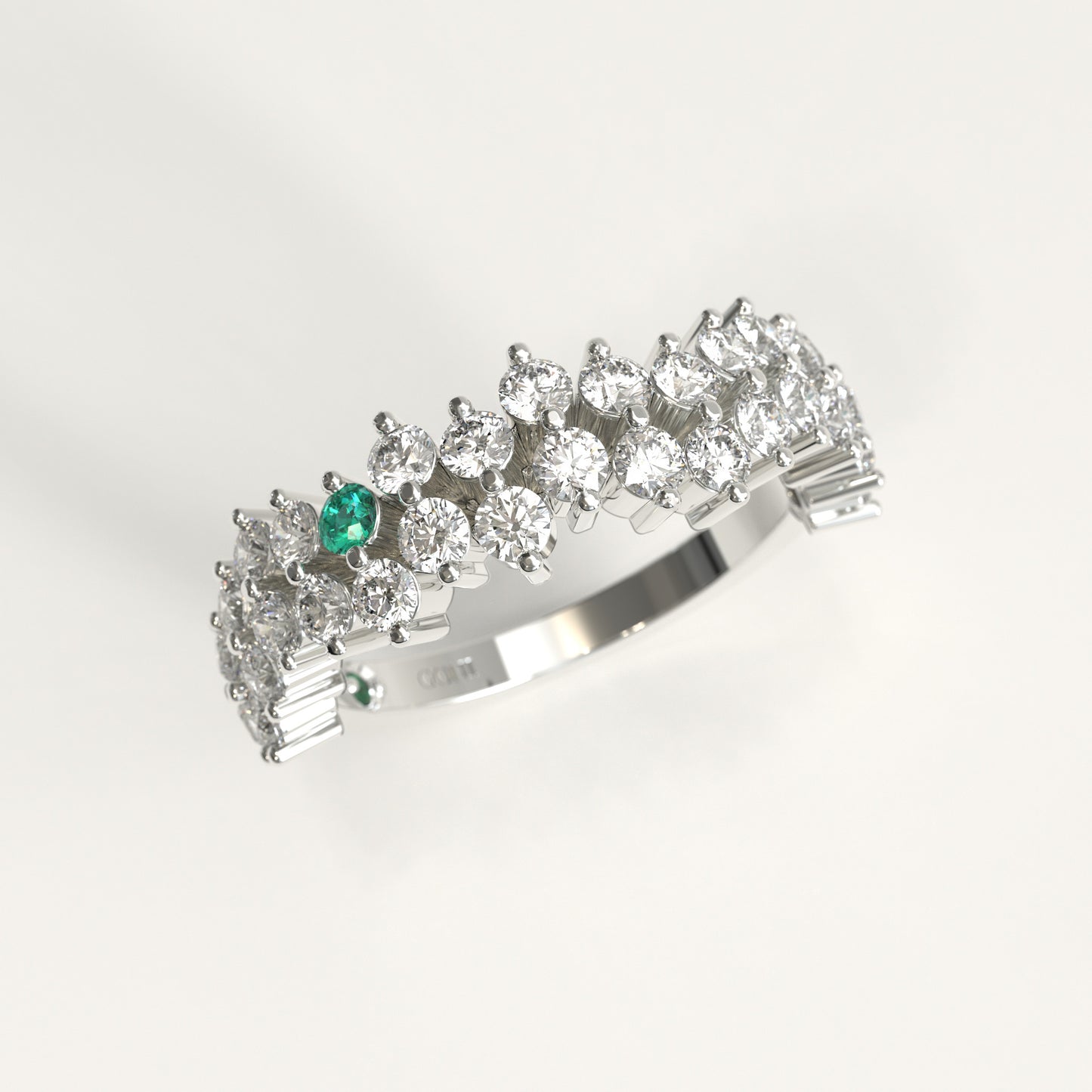 Stratum Ring in 18k fairmined white gold with a tiered row of round brilliant diamonds set in a zigzag pattern, and one round Colombian emerald bezel-set among them at the center. Smooth polished white gold band beneath the sparkling stone cluster