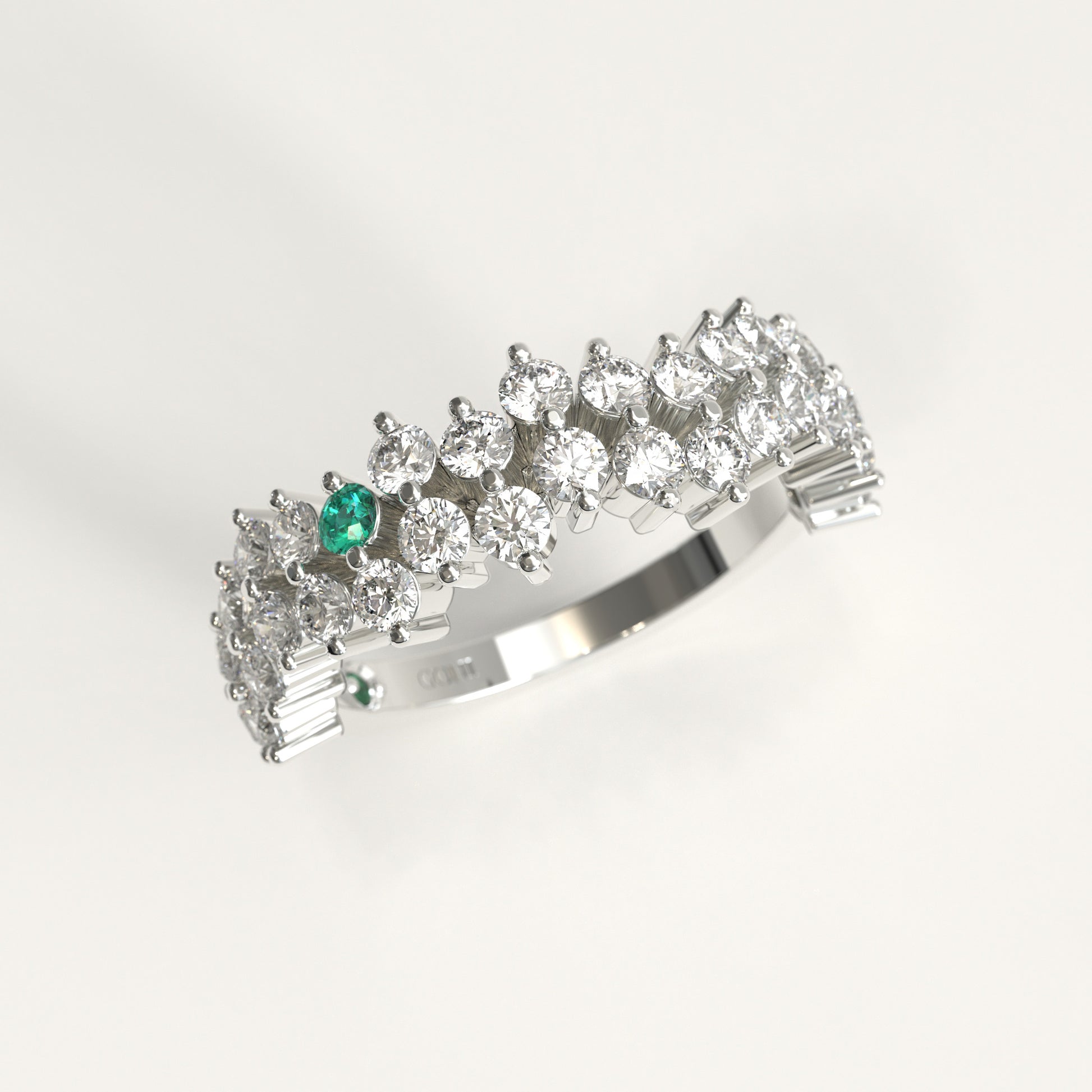 Stratum Ring in 18k fairmined white gold with a tiered row of round brilliant diamonds set in a zigzag pattern, and one round Colombian emerald bezel-set among them at the center. Smooth polished white gold band beneath the sparkling stone cluster