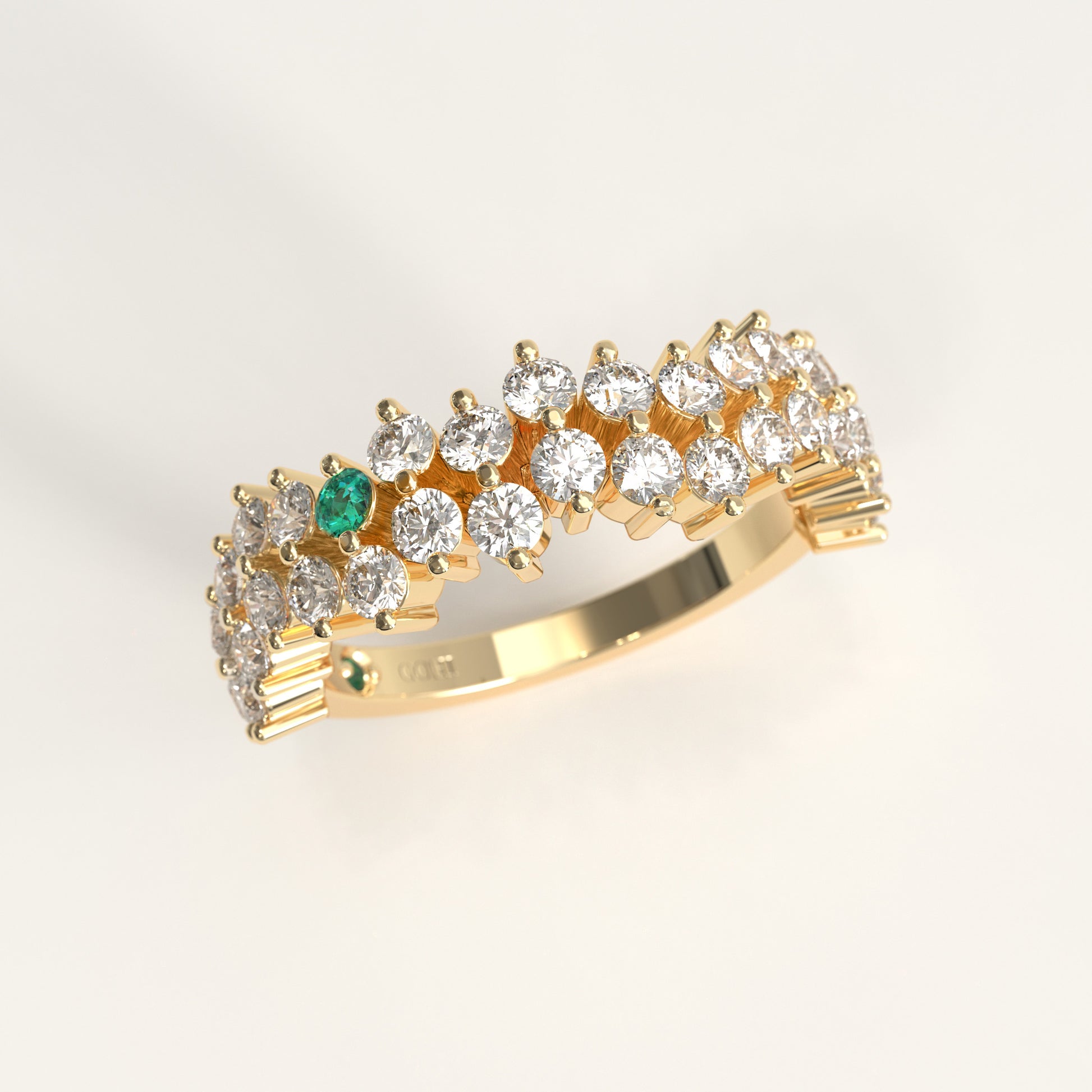 Stratum Ring in 18k fairmined yellow gold with a tiered row of round brilliant diamonds set in a zigzag pattern, and one round Colombian emerald bezel-set among them at the center. Smooth polished white gold band beneath the sparkling stone cluster