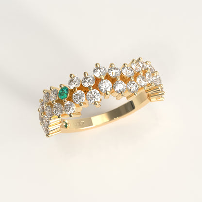 Stratum Ring in 18k fairmined yellow gold with a tiered row of round brilliant diamonds set in a zigzag pattern, and one round Colombian emerald bezel-set among them at the center. Smooth polished white gold band beneath the sparkling stone cluster