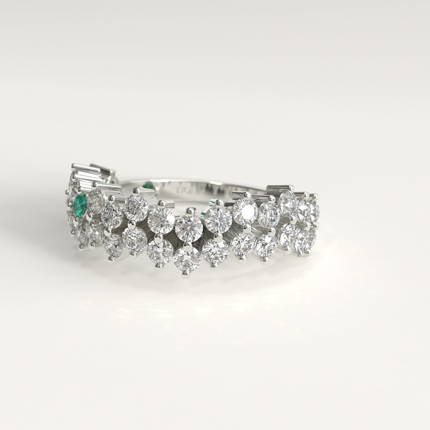 lateral view of Stratum Ring in 18k fairmined white gold with a tiered row of round brilliant diamonds set in a zigzag pattern, and one round Colombian emerald bezel-set among them at the center. Smooth polished white gold band beneath the sparkling stone cluster
