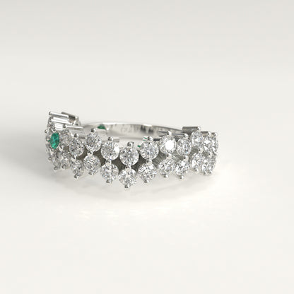 lateral view of Stratum Ring in 18k fairmined white gold with a tiered row of round brilliant diamonds set in a zigzag pattern, and one round Colombian emerald bezel-set among them at the center. Smooth polished white gold band beneath the sparkling stone cluster