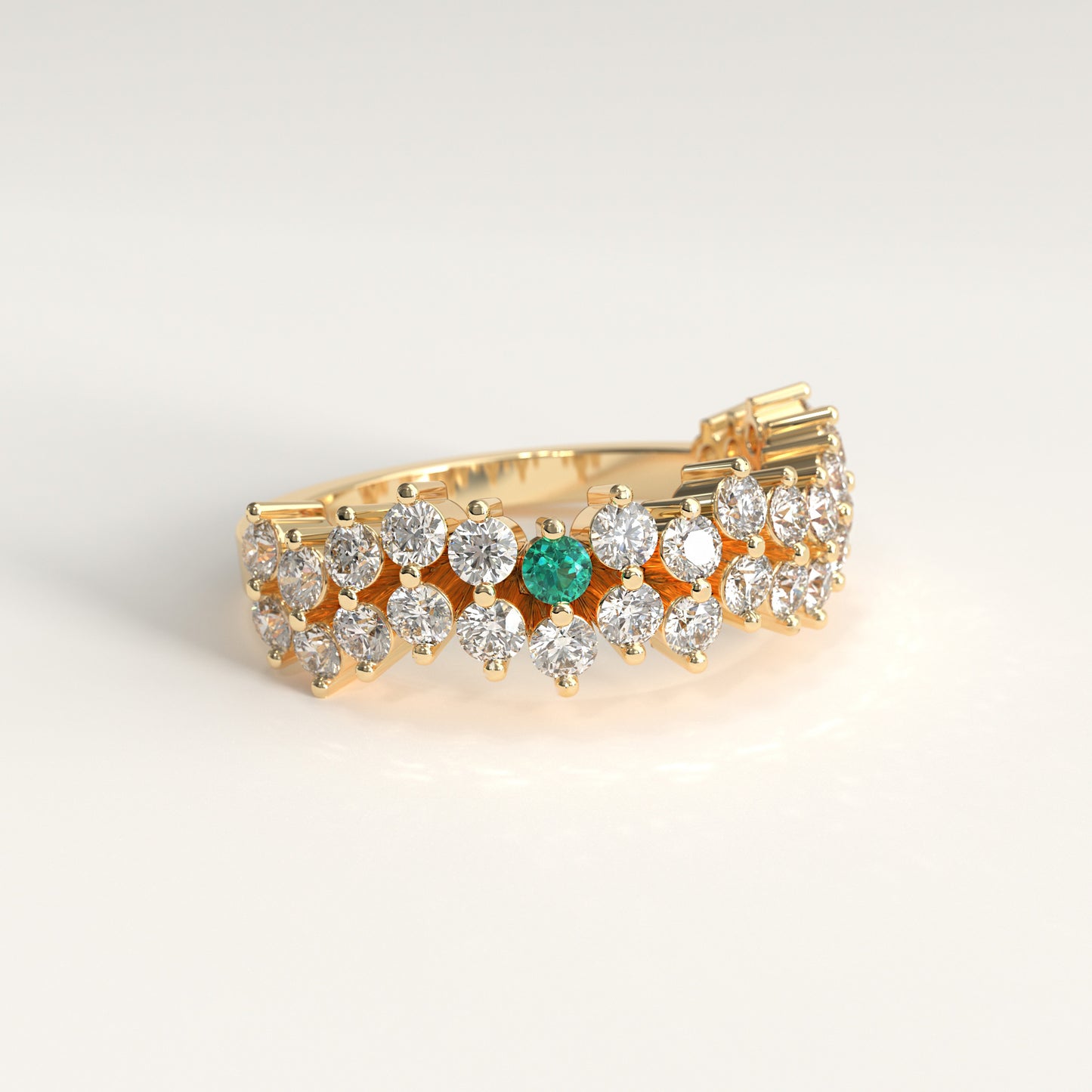 Stratum Ring in 18k fairmined yellow gold with a tiered row of round brilliant diamonds set in a zigzag pattern, and one round Colombian emerald bezel-set among them at the center. Smooth polished white gold band beneath the sparkling stone cluster