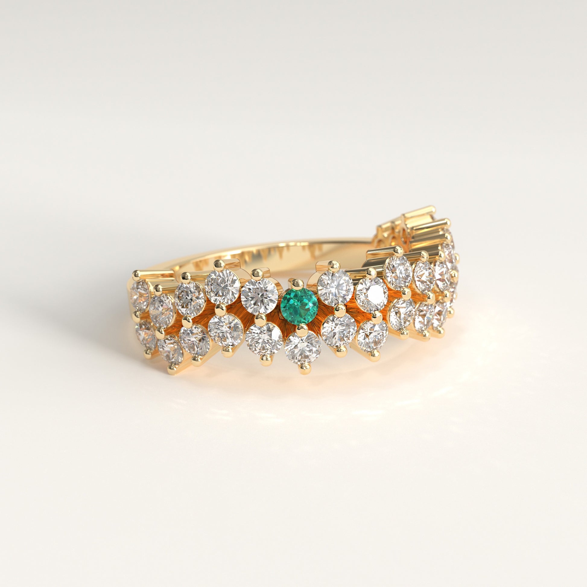 Stratum Ring in 18k fairmined yellow gold with a tiered row of round brilliant diamonds set in a zigzag pattern, and one round Colombian emerald bezel-set among them at the center. Smooth polished white gold band beneath the sparkling stone cluster