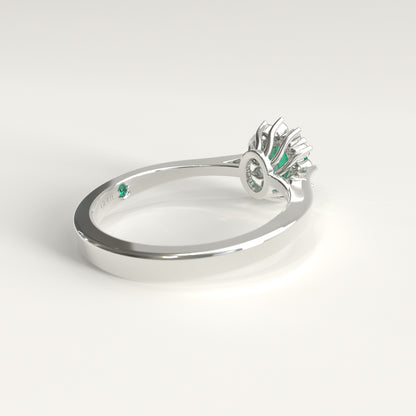 Back view of the ring's underside, showing the gold prongs cradling the emerald from below and, just beside the GOHI signature engraved inside the band, a tiny hidden emerald catching a glint of green.