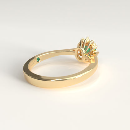 Back view of the ring's underside, showing the gold prongs cradling the emerald from below and, just beside the GOHI signature engraved inside the band, a tiny hidden emerald catching a glint of green.