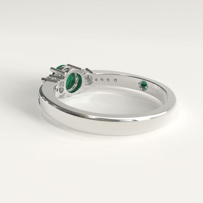 Back view of the ring's underside, showing the prong settings holding the emerald and diamonds from below, with the GOHI signature engraved inside the band beside a tiny hidden emerald.