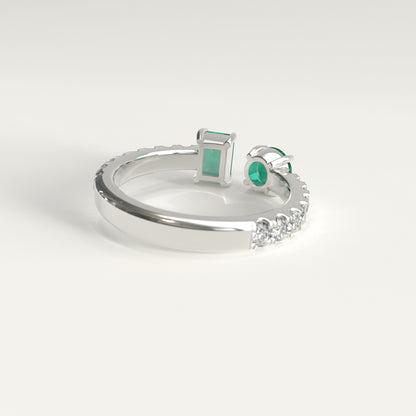 Back view of Duet Ring showing hidden Colombian emerald beside GOHI signature, 18k white gold. A white gold ring with a rectangular emerald-cut xolombian emerald and a round green colombian emerald, accented by small diamonds along the band, shown on a light gray background.