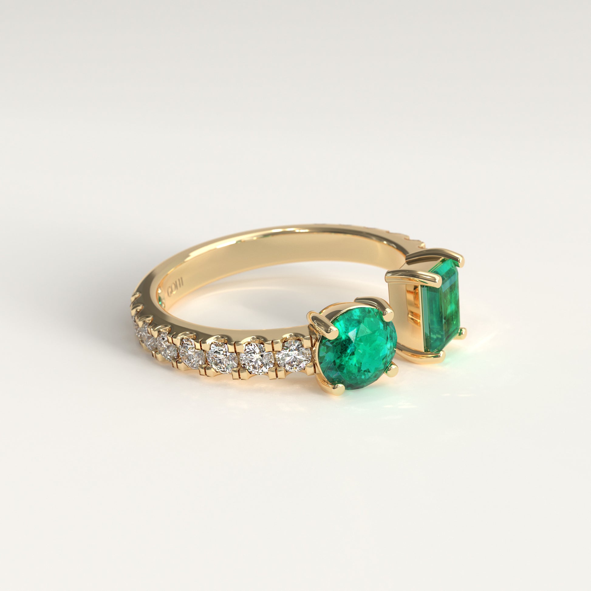 Lateral view of Duet Ring showing hidden Colombian emerald beside GOHI signature, 18k yellow gold. A yellow gold ring featuring a round colombian emerald emerald-cut on one side and a row of small clear pavé-set round diamonds on the other, photographed on a clean white background.