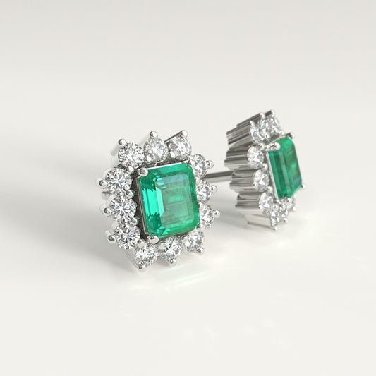 Lateral view of a pair of white gold stud earrings featuring rectangular emerald-cut colombian emerald surrounded by small diamonds, photographed on a clean white background.
