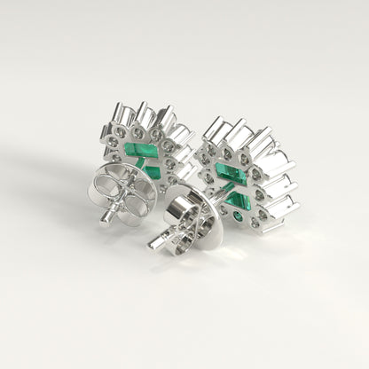 Back  view of a pair of white gold stud earrings with a textured, geometric design featuring small diamonds and rectangular colombian emerald inset accents, displayed on a clean light gray background.