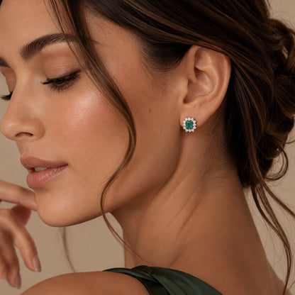woman with white gold stud earrings featuring rectangular emerald-cut colombian emerald surrounded by small diamonds, photographed on a clean white background.
