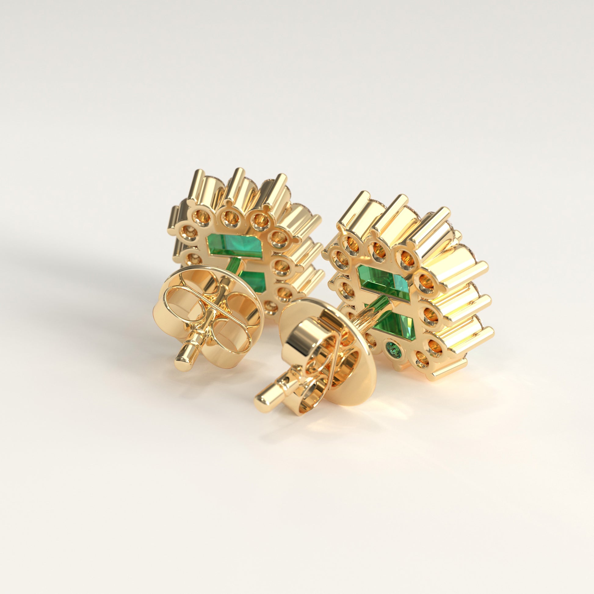 Back view of a pair of yellow gold stud earrings with rectangular colombian emerald inlays and small emerald accent stones, shown on a clean light gray background.