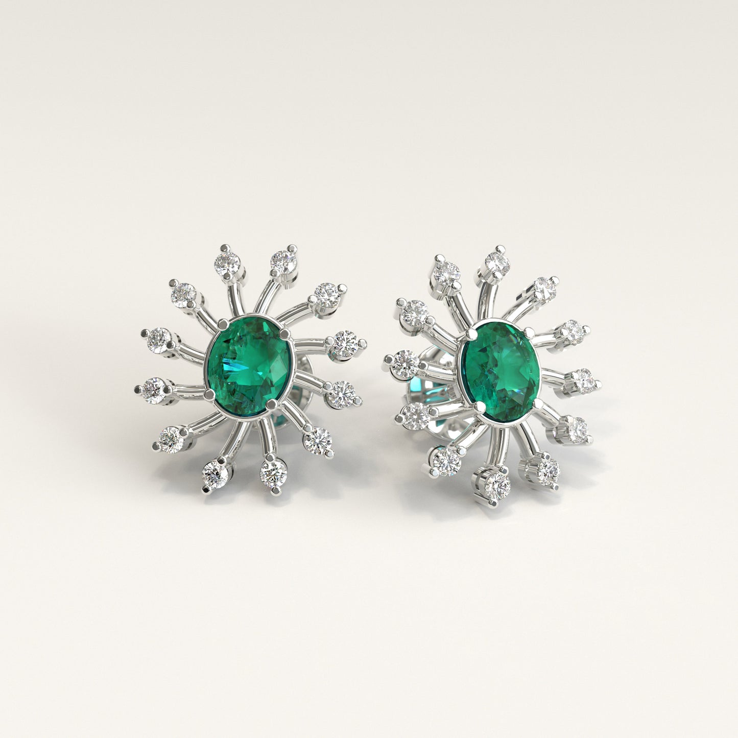 A pair of White gold starburst stud earrings, each featuring a oval colombian emerald center stone surrounded by smaller natural diamonds, shown on a light beige background.