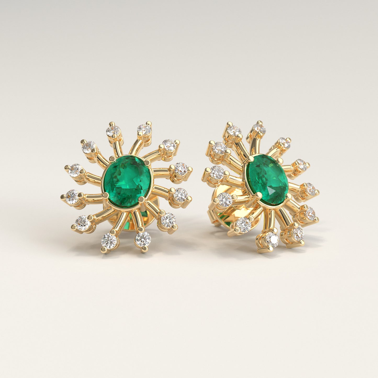 Nova Earrings in 18k yellow gold — Colombian emerald and diamond burst stud earrings, Soiree Collection by GOHI. A pair of 18k yellow gold starburst stud earrings, each featuring a central oval colombian emerald stone surrounded by smaller round diamonds, shown on a light beige background.