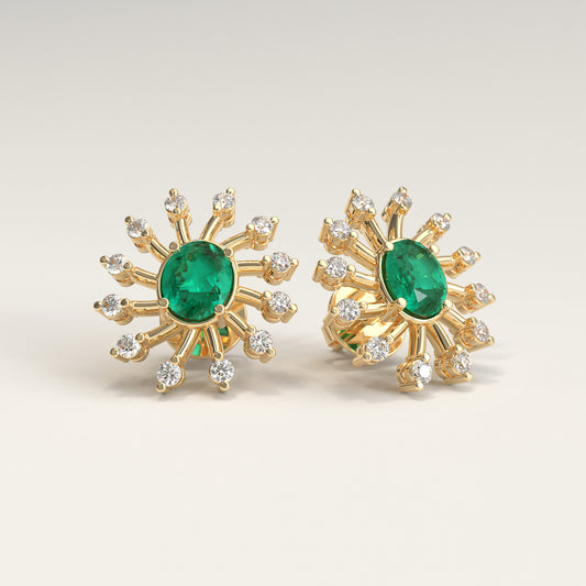 Nova Earrings in 18k yellow gold — Colombian emerald and diamond burst stud earrings, Soiree Collection by GOHI. A pair of 18k yellow gold starburst stud earrings, each featuring a central oval colombian emerald stone surrounded by smaller round diamonds, shown on a light beige background.